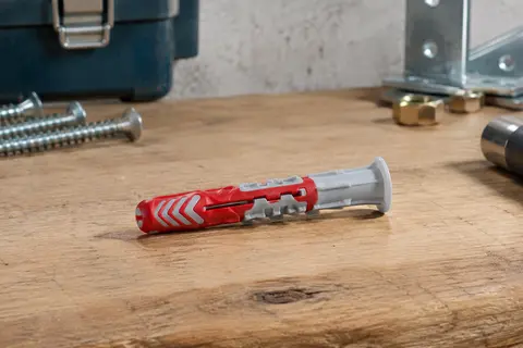Chevilles nylon bi-matière Fischer DuoPower posées sur un établi en bois clair.