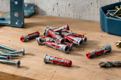 Chevilles Fischer DuoPower rouges et grises de 6 x 30 mm disposées sur un établi en bois