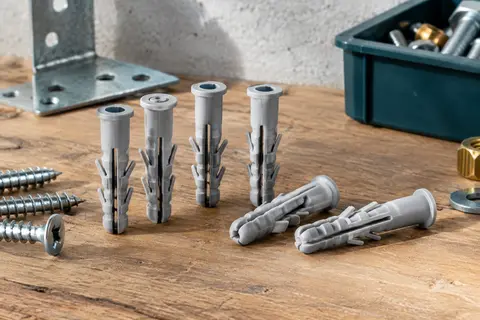 Chevilles nylon grises Fischer SX Plus à expansion quadruple posées sur un établi en bois