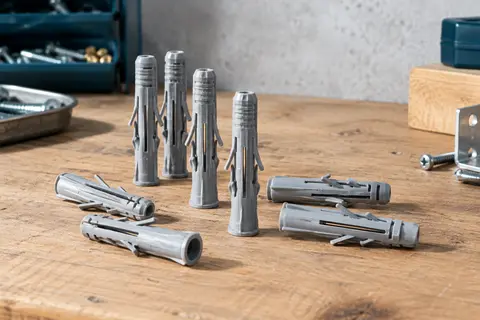 Chevilles nylon grises Fischer SX Plus disposées sur un établi, ailettes et nervures visibles.