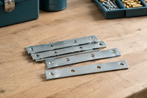 Plaques d’assemblage plates en acier galvanisé présentées sur un établi en bois brut.