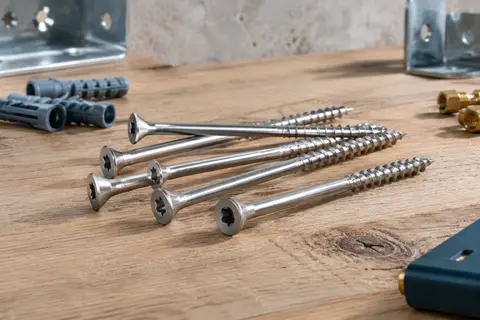 Vis de terrasse en acier argenté avec tête fraisée TX et pointe Cut, posées sur un établi en bois brut.